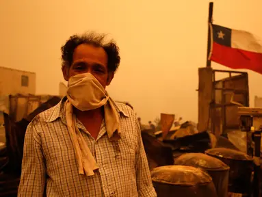 Warga berdiri menggunakan masker selama kebakaran hutan di Santa Olga, Chile, (26/1). Chile dilanda kebakaran hutan terbesar yang menghanguskan ratusan rumah, sejumlah fasilitas umum, dan juga sekolah. (Javier Torres/Aton via AP)