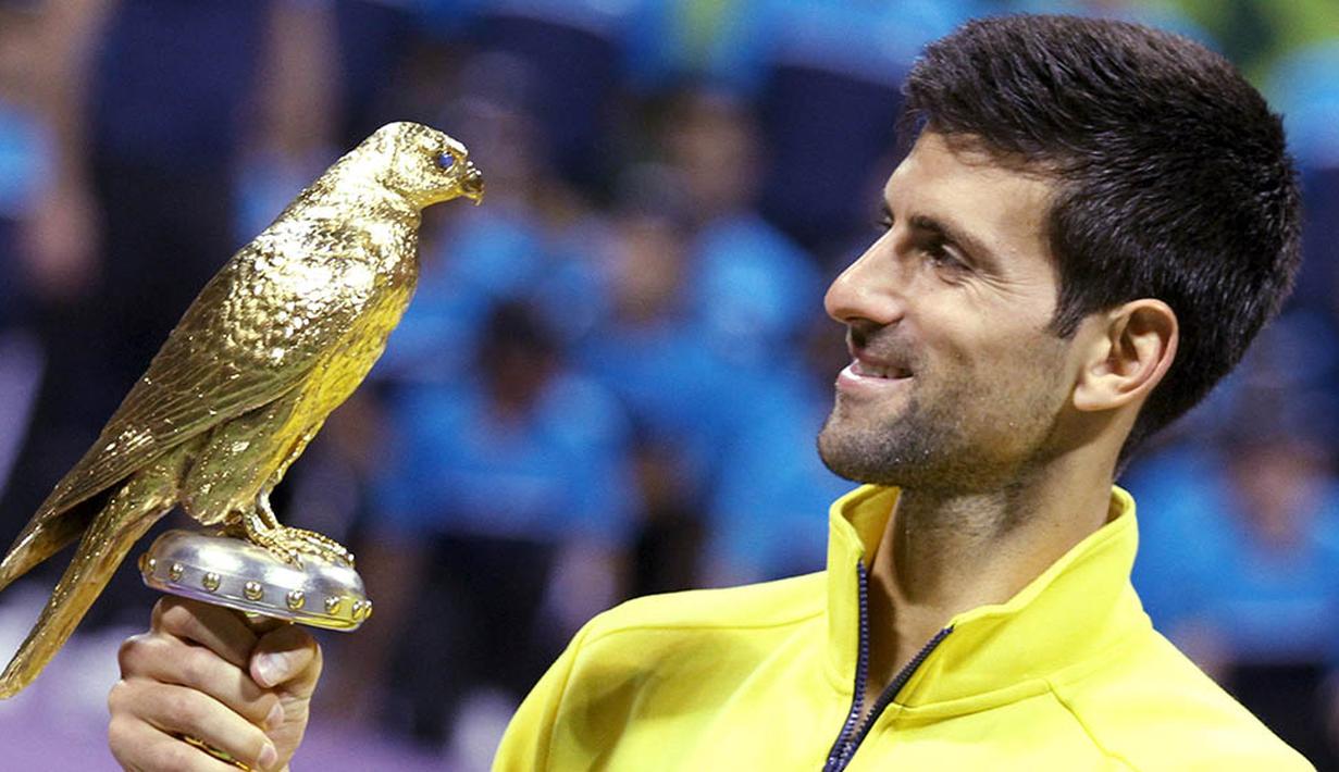 Petenis Serbia, Novak Djokovic, memegang piala usai menjadi pemenang tunggal putra Qatar Open di Doha, Minggu (10/1/2016). Pada laga final dirinya mengalahkan Rafael Nadal. (Reuters/Naseem Zeitoon)