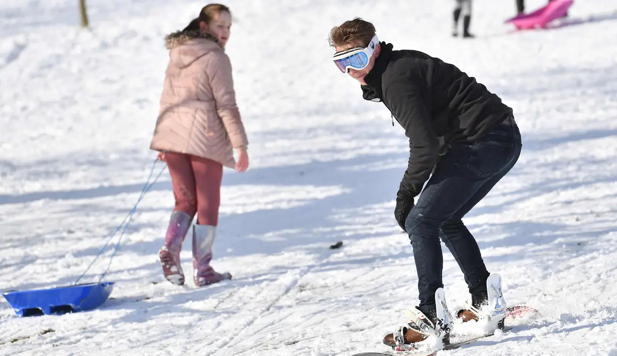 Seorang pria bermain snowboard di taman Dunorlan di Tunbridge Wells, Inggris (27/2). Cuaca dingin di Siberia yang dijuluki "The Beast from the East" membuat suhu di sebagian Eropa menurun. (AFP Photo/Ben Stansall)