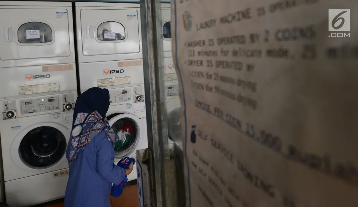 Seorang ibu rumah tangga menaruh cucian di sebuah laundry koin di Jakarta, Sabtu (8/6). Pada libur Lebaran, jasa laundry ramai didatangi konsumen, terutama oleh mereka yang ditinggal mudik asisten rumah tangganya. (merdeka.com/Imam Buhori)