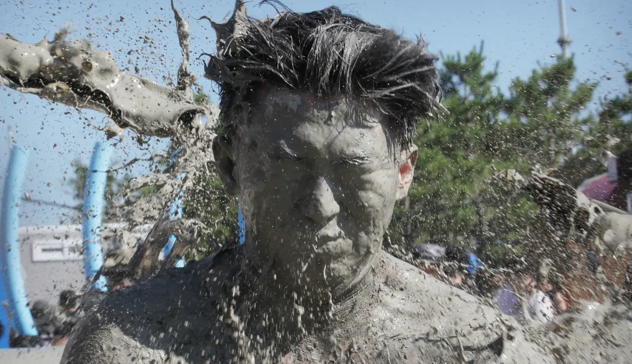 Wajah seorang pria terkena air lumpur selama Festival Lumpur Boryeong di Pantai Daecheon di Boryeong, Korea Selatan, (14/7). Festival lumpur tahunan ke-21 ini menampilkan gulat lumpur. (AP Photo / Ahn Young-joon)
