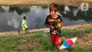 Anak-anak bermain di sekitar bantaran Kanal Banjir Timur (KBT), kawasan Cipinang Muara, Jakarta, Selasa (16/6/2020). Sebagian besar warga masih mengabaikan protokol kesehatan dengan tidak menjaga jarak serta tanpa menggunakan masker. (Liputan6.com/Immanuel Antonius)