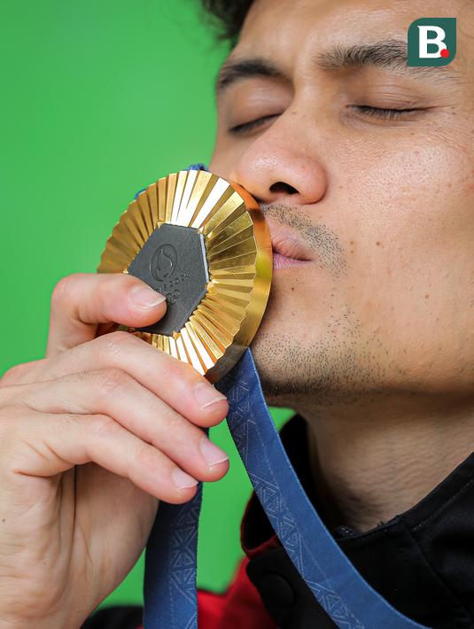 Atlet panjat tebing Indonesia, Veddriq Leonardo mencium medali emas Olimpiade Paris 2024 saat ditemui di markas FPTI, Hotel Santika Premier, Bekasi, Selasa (20/08/2024). (Bola.com/Bagaskara Lazuardi)