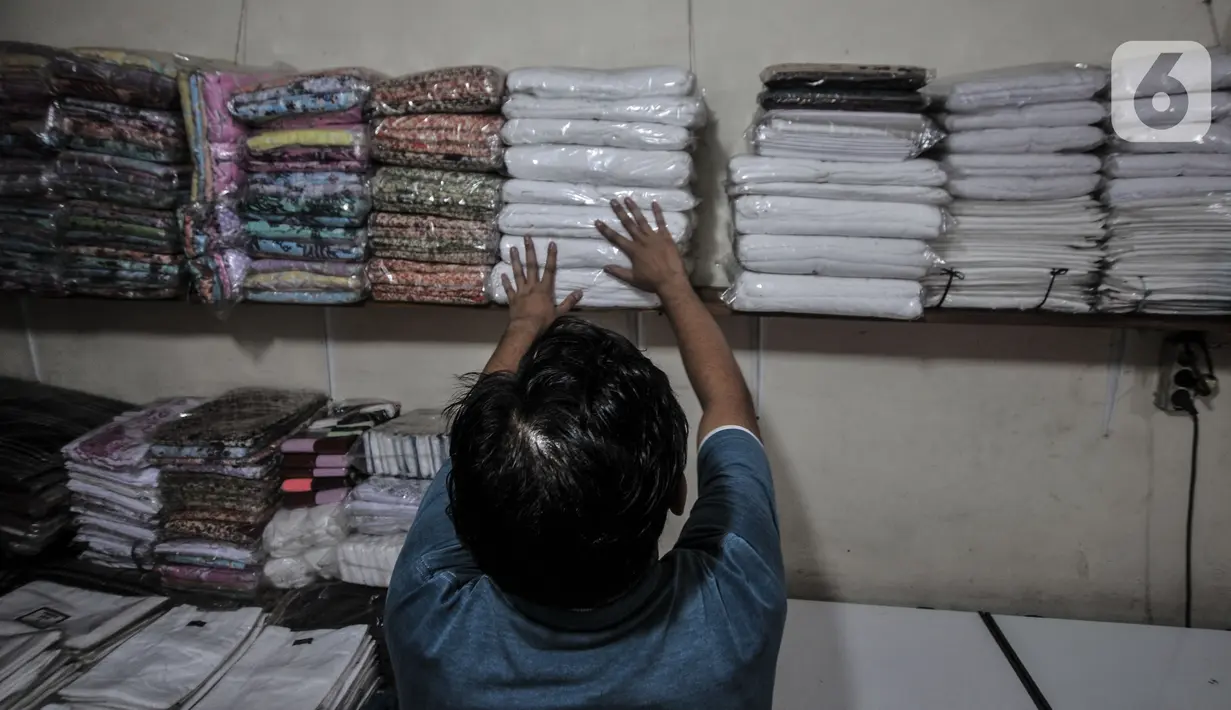 Pekerja saat merapikan kain ihram yang telah lama berada di rak toko miliknya di Jalan Raya Pondok Gede, Jakarta, Rabu (21/7/2021). (merdeka.com/Iqbal S. Nugroho)