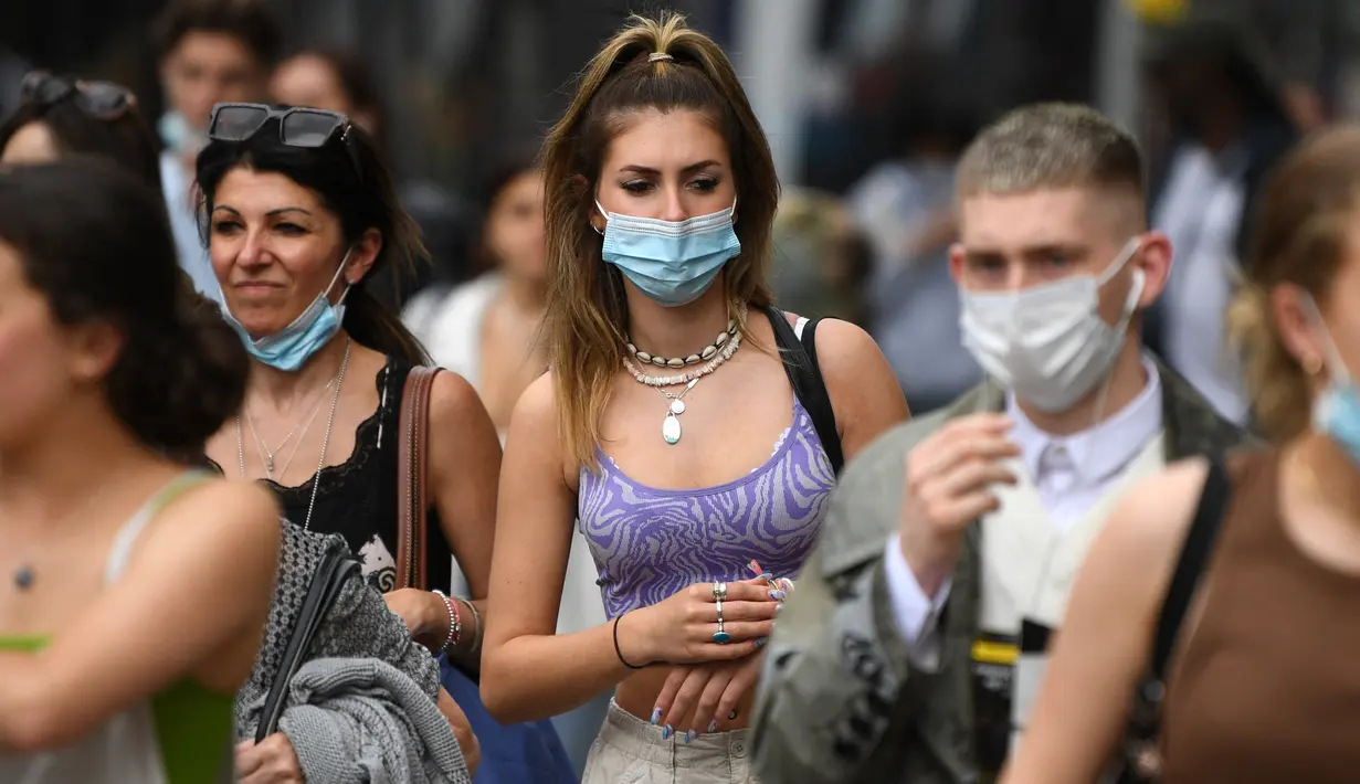 Pembelanja yang mengenakan masker berjalan di sepanjang Oxford Street di pusat kota London, Senin (5/7/2021). PM Inggris Boris Johnson berencana mencabut sebagian besar pembatasan wilayah selama pandemi Covid-19, termasuk penggunaan masker dan jaga jarak mulai 19 Juli. (DANIEL LEAL-OLIVAS/AFP)