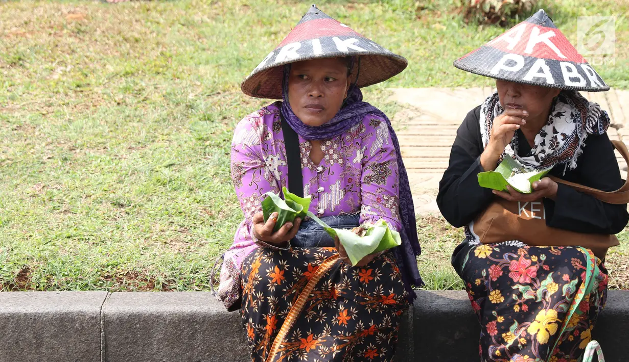 Sejumlah petani Kendeng menyantap makanan saat aksi di depan Istana Negara, Jakarta, Kamis (2/8). Dalam aksinya, mereka melakukan tradisi Brokohan atau makan bersama nasi aneka urap yang sebelumnya didoakan. (Liputan6.com/Helmi Fithriansyah)
