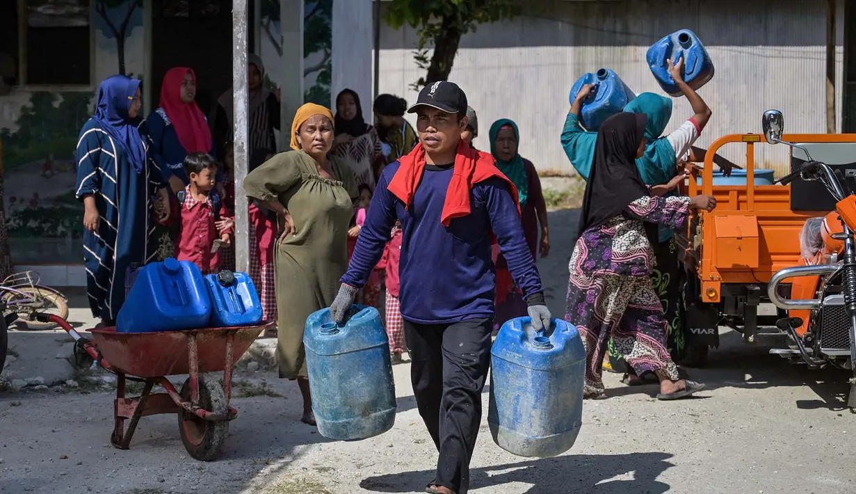 Warga membawa jeriken saat pendiistribusian air bersih oleh Palang Merah Indonesia (PMI) Kabupaten Bangkalan di Dusun Batangan Tengah, Desa Batangan, Kecamatan Tanah Merah, Kabupaten Bangkalan, Jawa Timur, Selasa (21/7/2026). (AFP/ Juni Kriswanto)