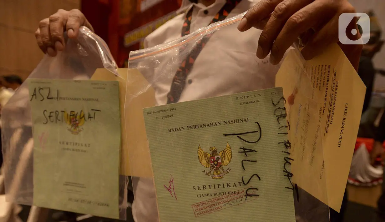 Petugas menunjukkan perbedaan sertifikat tanah asli dan palsu saat rilis kasus sindikat mafia tanah di Jakarta, Rabu (12/2/2020). Subdit II Harda Ditreskrimum Polda Metro Jaya bersama Kementerian ATR/BPN berhasil mengungkap sindikat mafia tanah dan menahan 10 tersangka. (merdeka.com/Imam Buhori)
