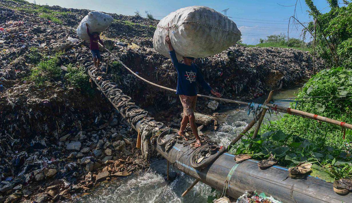 Warga menyebrangi Kali Pesanggrahan yang menyempit akbat longsoran timbunan sampah TPA Cipayung di kawasan Pasir Putih, Depok, Jawa Barat, Senin (27/04/2026), setelah longsoran sampah dari Tempat Pembuangan Akhir (TPA) Cipayung menutup sebagian badan sungai. (merdeka.com/Arie Basuki)