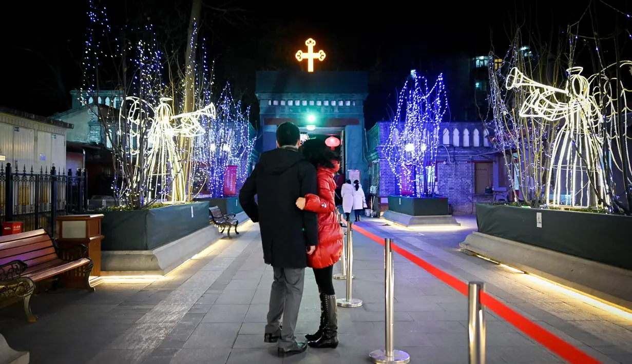 Pasangan suami istri foto bersama sebelum menghadiri Misa Malam Natal di sebuah gereja Katolik di Beijing (24/12). (AFP Photo/Wang Zhao)