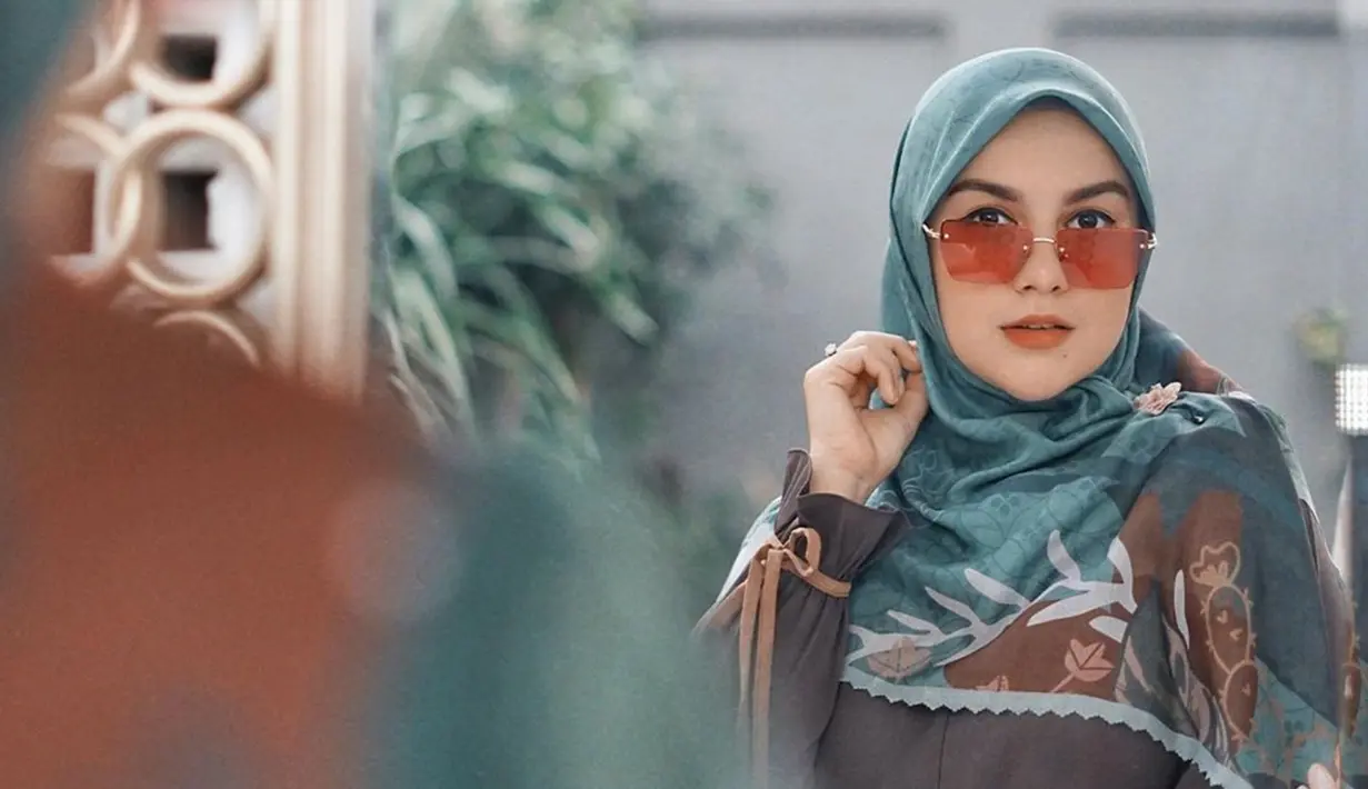 Penampilannya semakin lengkap dengan aksesoris kacamata berwarna oranye ini. Cocok dengan balutan hijabnya yang juga memiliki corak berwarna senada. (Liputan6.com/IG/@_irishbella_)