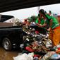 Petugas PPSU DKI Jakarta menaikkan sampah sisa banjir ke atas mobil di bawah Tol Becakayu, Cipinang Melayu, Jakarta Timur, Rabu (8/1/2020). Sampah sisa banjir tersebut selanjutnya diangkut ke TPA Bantar Gebang. (merdeka.com/Magang/Muhammad Fayyadh)