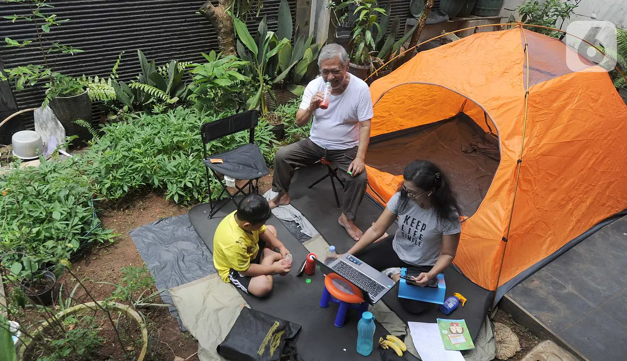 Warga bekerja menggunakan laptop di halaman rumahnya di kawasan Cinere, Depok, Senin (23/3/2020). Imbauan pemerintah untuk bekerja dari rumah atau work from home untuk mencegah penularan virus corona, dimanfaatkan warga dengan beragam aktivitas. (merdeka.com/Arie Basuki)