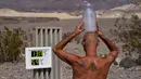 Suhu di Death Valley Capai 54,4 Derajat Celsius: Steve Krofchik mendinginkan kepalanya dengan botol berisi es batu di Taman Nasional Death Valley, California, Senin (17/8/2020). Temperatur udara tertinggi di Dunia -- 54,4 derajat Celcius -- tercatat di Death Valley pada 16 Agustus. (AP/John Locher)