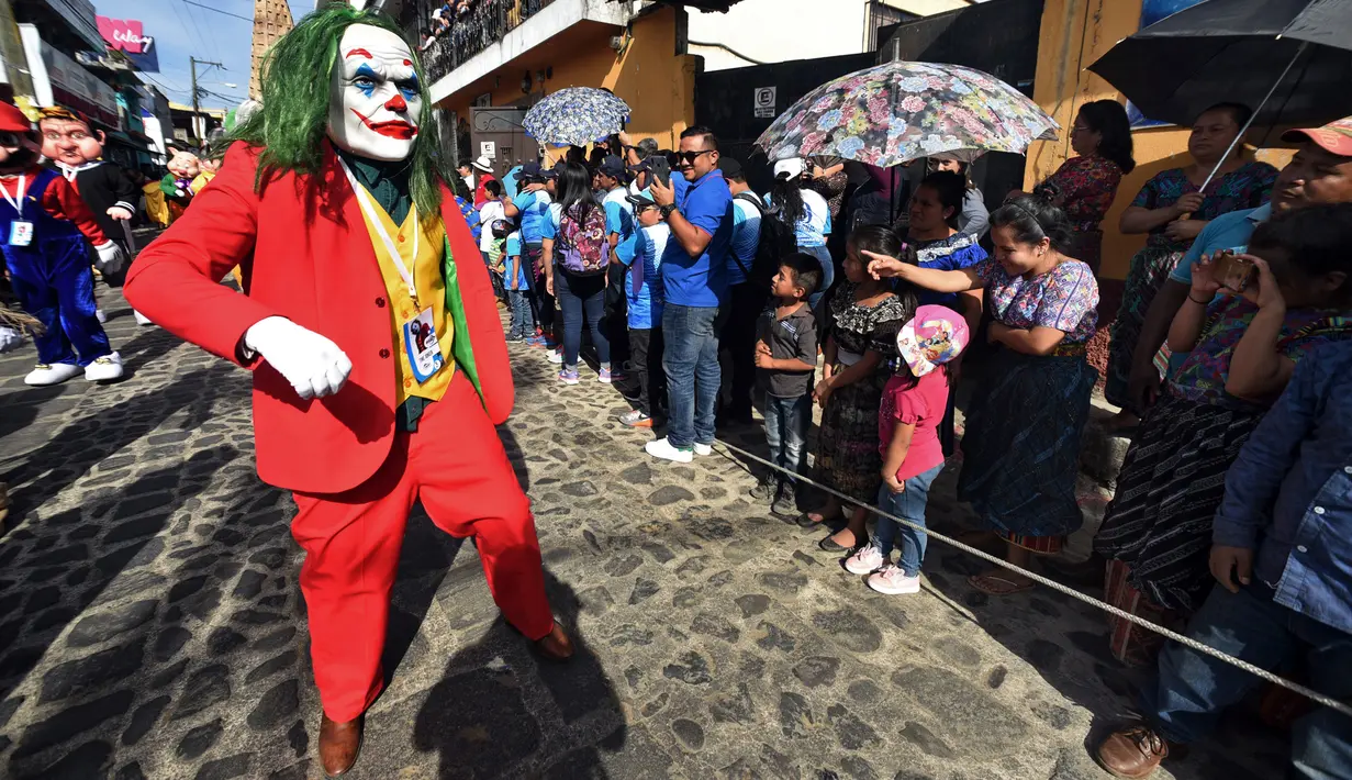 Anggota Saturno Club dengan kostum Joker melakukan parade Dance of Costumes tahunan di sepanjang jalan kota Sumpango, Guatemala, Senin (30/12/2019). Parade kostum yang menampilkan karakter televisi dan film ini untuk memeriahkan malam pergantian tahun. (ORLANDO ESTRADA/AFP)