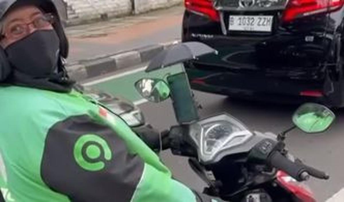 Namun jangan salah, si ojol tersebut rupanya punya cara unik untuk melindungi ponsel miliknya. Dia menggunakan payung kecil.&nbsp;