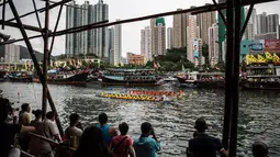 Para penonton melihat sejumlah tim bersaing dalam peringatan tahunan Tuen Ng atau Festival Perahu Naga di Hong Kong, Kamis (9/6). Perahu yang berukuran 10 meter itu diukir berbentuk kepala naga dan ekornya. (Anthony WALLACE/AFP)