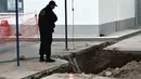Seorang polisi mengamati sebuah lubang ditemukannya bom dari masa Perang Dunia II di Kota Thessaloniki, Yunani, 9 Februari 2017. Penemuan bom yang mengandung sekitar 250 kg bahan peledak itu memicu evakuasi sekitar 60 ribu warga. (SAKIS MITROLIDIS/AFP)