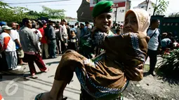 Anggota TNI menggendong seorang nenek ketika pembagian sembako oleh Presiden Joko Widodo atau Jokowi di halaman Gedung Graha Saba, Solo, Jawa Tengah, Jumat (8/7). Keluarga Jokowi membagikan 2.200 paket sembako kepada warga Solo (Liputan6.com/Boy Harjanto)