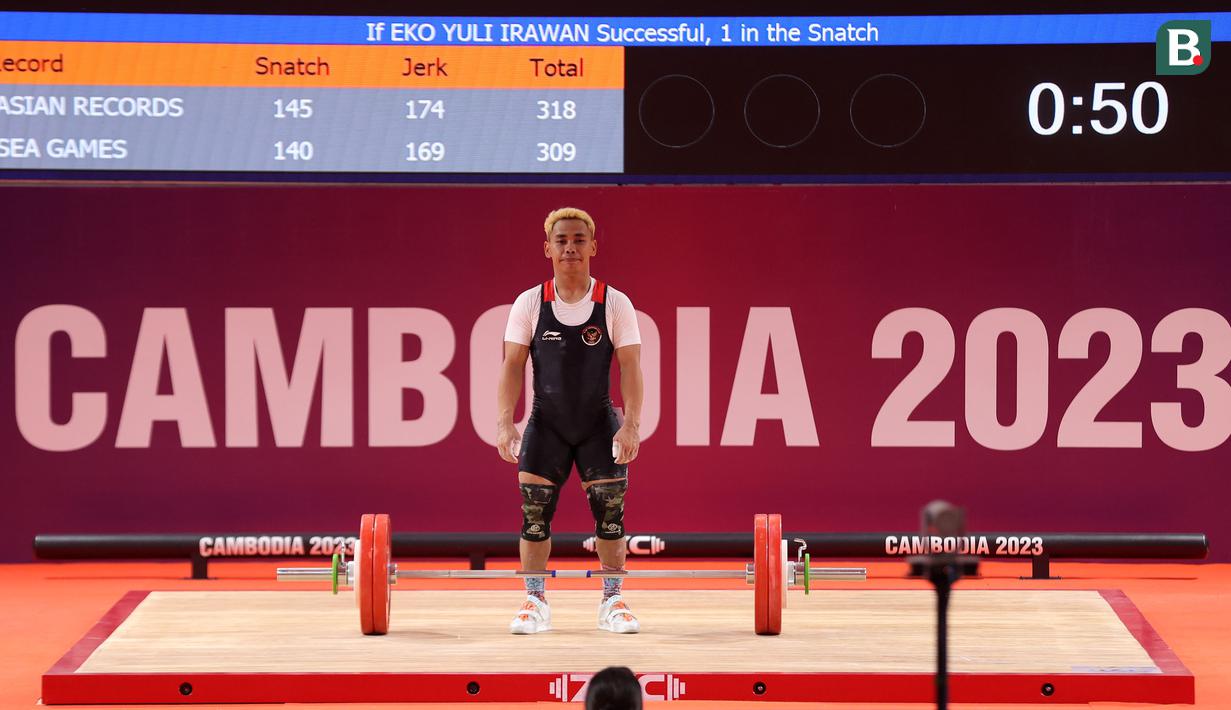 <p>Atlet angkat besi Indonesia, Eko Yuli Irawan berkompetisi pada nomor angkat besi putra 61 kg SEA Games 2023 di Taekwondo Hall Olympic Complex, Phnom Penh, Kamboja, Sabtu (13/05/2023). (Bola.com/Abdul Aziz)</p>