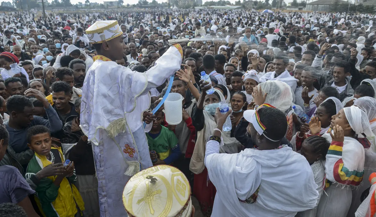 Umat Kristen Ortodoks Ethiopia disemprot dengan air dalam upacara untuk merayakan hari kedua festival Timkat, atau Epiphany, di ibu kota Addis Ababa, Ethiopia, Rabu (19/1/2022). Festival tahunan merayakan pembaptisan Yesus Kristus di Sungai Yordan. (AP Photo)