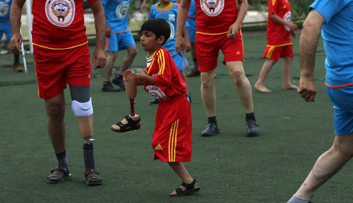 Seorang anak Irak memegang kaki palsunya saat bermain sepak bola di Arbil, Irak utara (7/5). Mereka semangat bermain sepak bola meski menggunakan kaki palsu. (AFP/Safin Hamed)