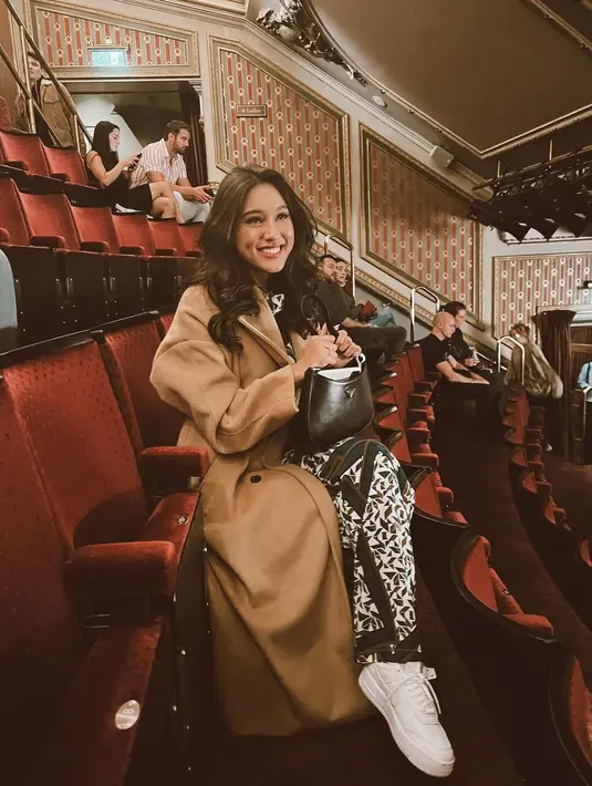 OOTD Yasmine Napper saat nonton musikal. Ia mengenakan setelan bermotif ditumpuk long coat wol berwarna cokelat, dipadu dengan sneakers putih dan mini bag hitam. [Foto: Instagram/yasminnapper]