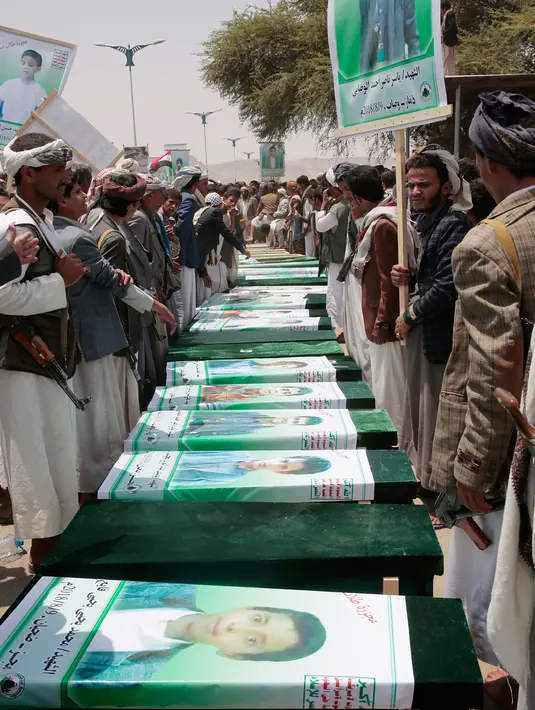 Warga Yaman menghadiri pemakaman puluhan bocah korban serangan koalisi Arab Saudi, di Saada, Senin (13/8). Warga membawa foto korban sementara pejuang Houthi mengatur mereka agar pemakaman berjalan aman. (AP/Hani Mohammed)