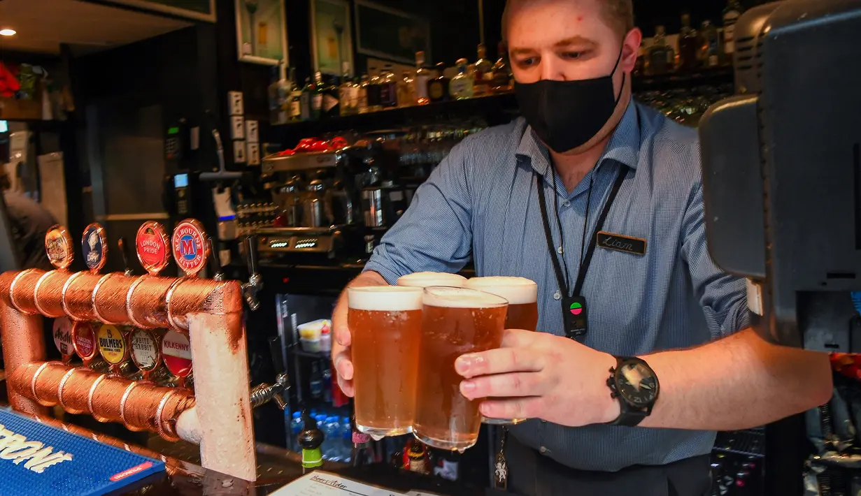 Seorang bartender menyajikan bir di sebuah pub di Melbourne, Australia, Jumat (22/10/2021). Saat ini, 70 persen warga Melbourne sudah divaksin sehingga kebijakan lockdown mulai bisa dilonggarkan. (William WEST/AFP)