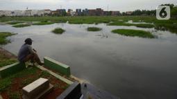 Warga memancing ikan di Tempat Pemakaman Umum (TPU) Semper yang terendam banjir, Jakarta, Kamis (11/11/2021). Ratusan makan di TPU Semper terendam banjir akibat hujan deras yang menguyur Ibu Kota beberapa hari lalu. (merdeka.com/Imam Buhori)