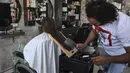 Dalam gambar pada 8 April 2021, tukang cukur Pakistan Ali Abbas menggunakan pisau daging untuk memotong rambut seorang pelanggan di tokonya di Lahore. Berharap membuktikan kemampuannya dalam persaingan, Ali Abbas mengandalkan berbagai alat yang tidak biasa untuk melatih keahliannya. (Arif ALI/AFP)