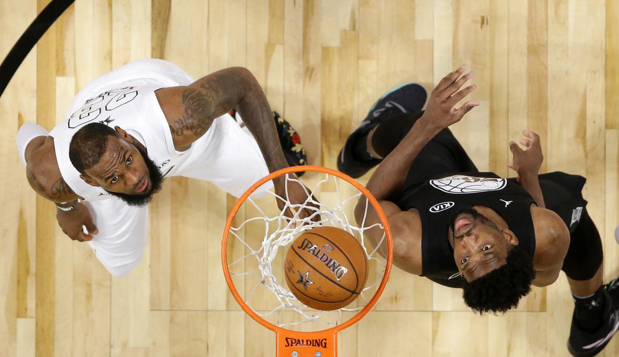 LeBron James (kiri) dan Joel Embiid melihat bola yang masuk ke dalam keranjang pada laga NBA All-Star basketball game di Los Angeles, (18/2/2018). Tim LeBron menang 148-145. (Mike Nelson/Pool via AP)