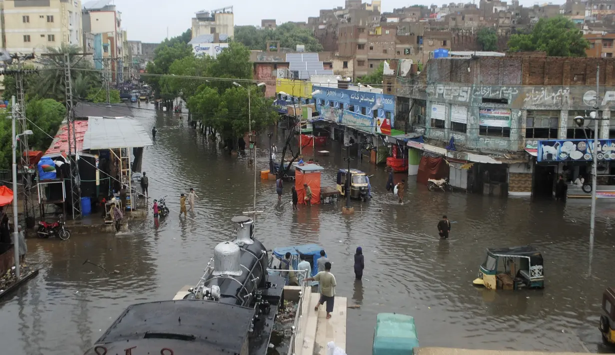 Orang-orang melewati jalan yang banjir setelah hujan monsun lebat, di Hyderabad, Pakistan, Rabu (24/8/2022). Hujan deras telah memicu banjir bandang dan mendatangkan malapetaka di sebagian besar Pakistan sejak pertengahan Juni, menyebabkan 903 orang tewas dan sekitar 50.000 orang kehilangan tempat tinggal, kata badan bencana negara itu. (AP Photo/Pervez Masih)