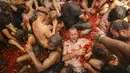 Orang-orang yang bersuka ria saling melempar tomat dalam acara tahunan "Tomatina", pesta pertarungan tomat di desa Bunol dekat Valencia, Spanyol, Rabu (31/8/2022). Pertarungan tomat terjadi sekali lagi setelah penangguhan selama dua tahun karena pandemi virus corona covid-19. (AP Photo/Alberto Saiz)