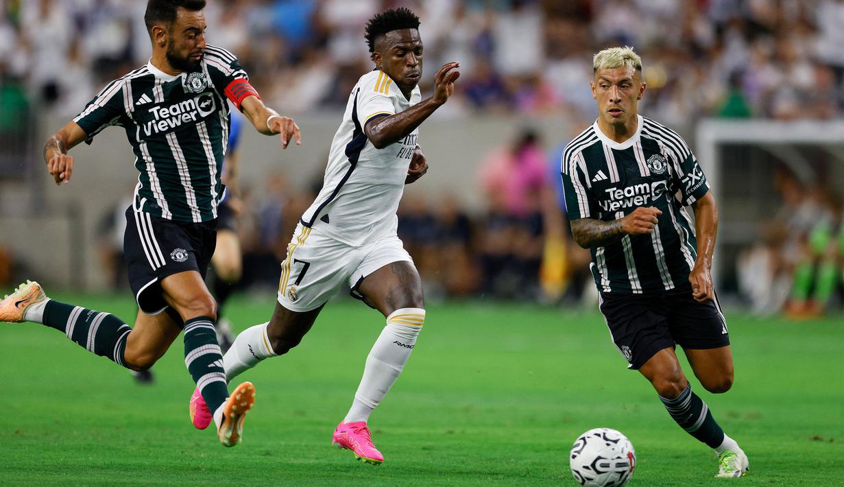 Pemain Real Madrid, Vinicius Jr (tengah), mengontrol bola dibayangi dua pemain MU, Bruno Fernandes (kiri) dan Lisandro Martinez, dalam pertandingan pramusim Soccer Champions Tour 2023 yang berlangsung di NRG Stadium, Houston, Kamis (27/7/23). (AFP/Getty Images/Tim Warner)