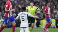 Jude Bellingham dari Real Madrid, bek tengah menghadap kamera, berdebat dengan wasit Jose Maria Sanchez Martinez saat pertandingan sepak bola La Liga Spanyol antara Real Madrid dan Atletico Madrid di stadion Santiago Bernabeu di Madrid, Spanyol, Minggu, 4 Februari 2024. ( Foto AP/Bernat Armangue)