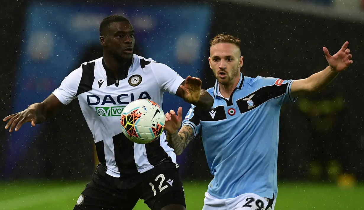 Gelandang Lazio, Manuel Lazzar, berebut bola dengan gelandang Udinese, Ken Sema, pada laga lanjutan Serie A pekan ke-33 di Dacia Arena, Kamis (16/7/2020) dini hari WIB. Lazio bermain imbang 0-0 atas Udinese. (AFP/Miguel Medina)