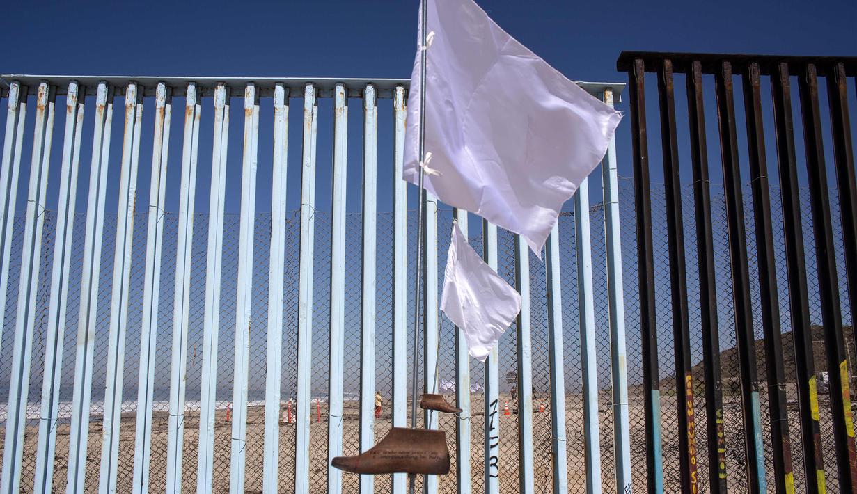 Pemandangan pagar perbatasan antara Meksiko dan Amerika Serikat yang dihiasi seni instalasi kontemporer "Tu huella es el camino, tu bandera es de paz" di Playas de Tijuana, Meksiko (7/10). (AFP Photo/Guillermo Arias)