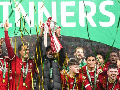 Pelatih Liverpool, Jurgen Klopp, mengangkat trofi juara Carabao Cup 2023/2024 di Stadion Wembley, Minggu (25/2/2024). The Reds menang lewat gol dramatis yang dicetak oleh Virgil van Dijk di menit Menit ke-118. (AP Photo/Alastair Grant)