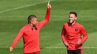 Pemain Paris Saint-Germain (PSG), Neymar (kanan) berbincang dengan Kylian Mbappe (kiri) saat sesi latihan di Paris Barat, Prancis, Senin (17/9). PSG akan menghadapi Liverpool di Liga Champions pada 19 September 2018. (Anne-Christine POUJOULAT/AFP)