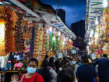 Orang-orang berjalan melintasi sepanjang toko yang menjual ornamen dan dekorasi menjelang Diwali, festival cahaya bagi umat Hindu, di distrik Little India di Singapura pada 23 Oktober 2020. (Photo by Roslan RAHMAN / AFP)