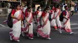Sekelompok siswa India yang mengenakan masker kembali dari sekolah mereka di Kolkata, 3 Maret 2022. Para ahli optimis bahwa lonjakan omicron, yang membawa tingkat kematian yang relatif rendah, telah memperkuat kekebalan dari vaksin, yang tersebar luas di kawasan tersebut. (AP Photo/Bikas Das)