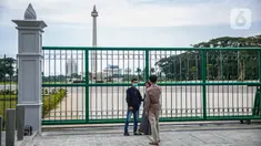 Warga berfoto di belakang Monumen Nasional atau Monas di Jakarta, Jumat (1/1/2021). Walaupun Monas ditutup warga tetap memanfaatkan libur Tahun Baru untuk berwisata dan berfoto di kawasan Monas. (Liputan6.com/Faizal Fanani)