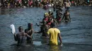 Para migran menyeberangi Rio Grande dari Del Rio, Texas, ke Ciudad Acuña, Meksiko, untuk berbelanja makanan sebelum kembali ke sisi perbatasan AS, Minggu (19/9/2021). Ribuan migran Haiti telah tiba di Del Rio, Texas, saat pihak berwenang berupaya menutup perbatasan.(AP Photo/Felix Marquez)
