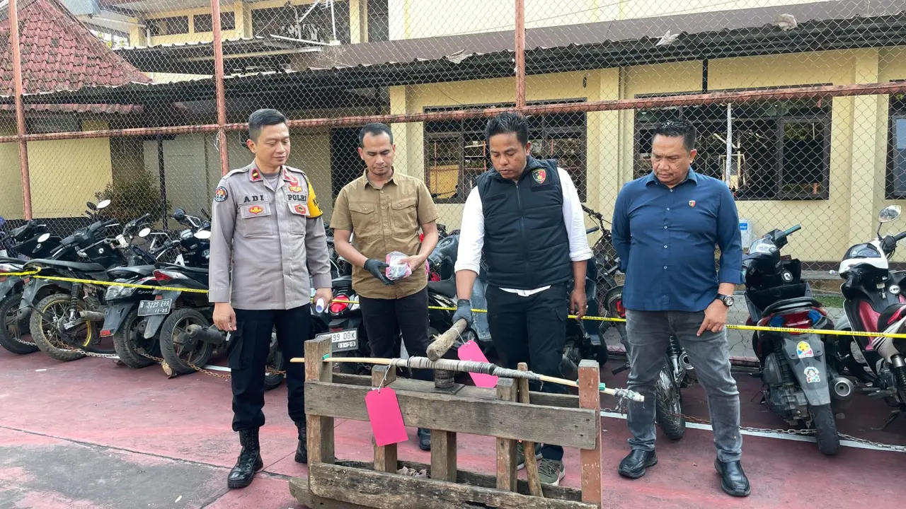 Kasatreskrim Polres Garut AKP Ari Rinaldo, bersama kasi Humas Polres Garut nampak menunjukan sebuah 'pidekan' atau alat yang biasa digunakan untuk praktek judi adu muncang. (Liputan6.com/Jayadi Supriadin)