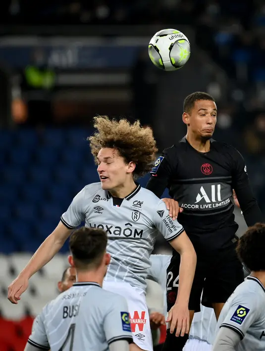 Bek Paris Saint-Germain (PSG) Thilo Kehrer (kanan) berebut bola dengan bek Reims Wout Faes (kiri) dalam matchday ke-22 Liga Prancis 2021/2022 di Parc des Princes, Senin (24/1/2022) dini hari WIB. PSG menang telak 4-0 atas Reims. (Franck FIFE / AFP)