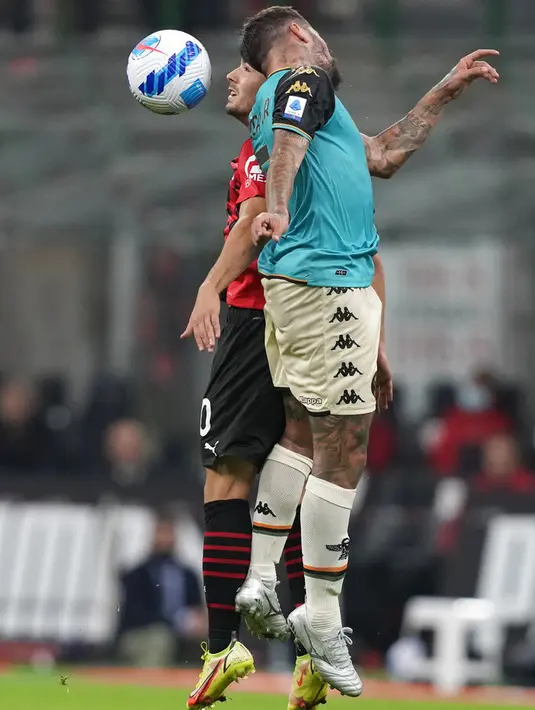 Gelandang Venezia, Antonio Junior Vacca dan penyerang AC Milan, Brahim Diaz melompat saat berebut bola pada laga pekan ke-5 Serie A 2021/22 di San Siro, Kamis (23/9/2021) dini hari WIB. AC Milan Milan menaklukkan tamunya Venezia 2-0. (AP Photo/Antonio Calanni)