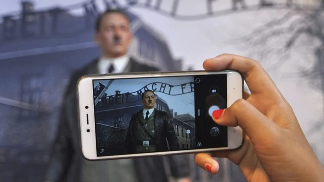 Pengunjung menggunakan ponsel untuk mengambil foto lilin Adolf Hitler berlatar belakang kamp Auschwitz di De Mata museum Yogyakarta, Indonesia (AP)