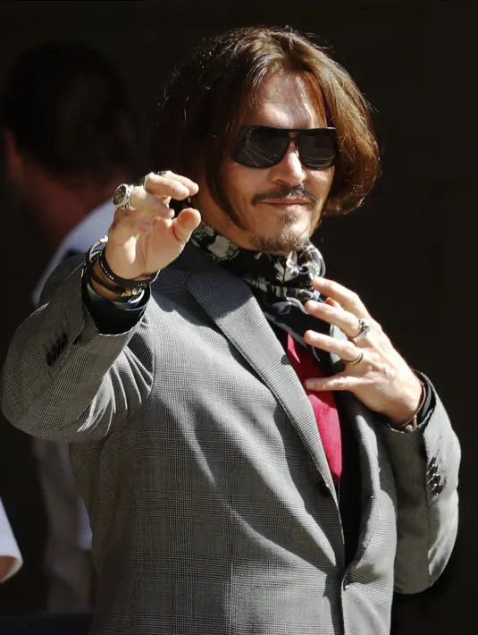 Aktor Johnny Depp memakai kacamata hitam dan syal saat menghadiri sidang pencemaran nama baik di Pengadilan Tinggi, London, Inggris, Selasa (21/7/2020). Johnny Depp menggugat tabloid The Sun atas artikel yang menyebut dirinya telah melakukan kekerasan terhadap sang istri. (AP Photo/Alastair Grant)