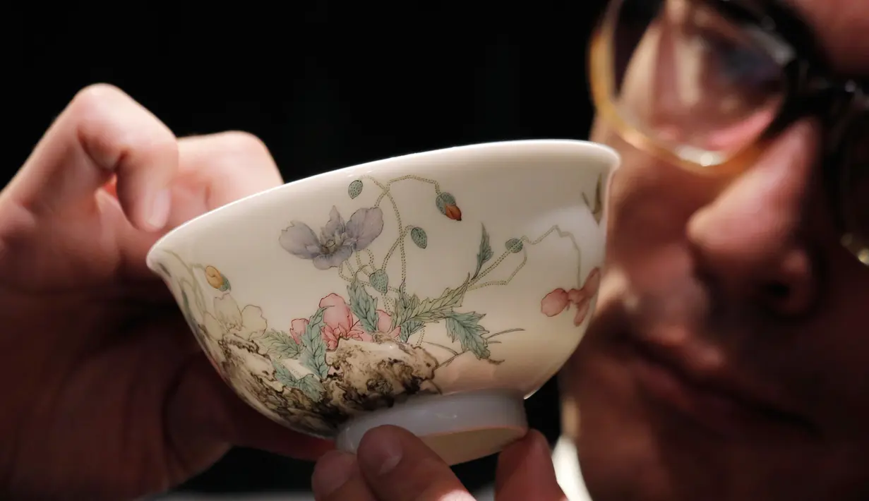 Pegawai rumah lelang Sotheby's memeng mangkuk falangcai dari Dinasti Qing selama pratinjau media di Hong Kong, Kamis (30/8). Mangkuk akan dilelang pada 3 Oktober 2018. (AP Photo/Kin Cheung)